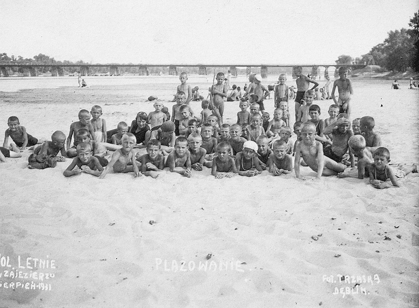 zdjęcie czrno-białe przedstawiające grupę dzieci leżącą na plaży