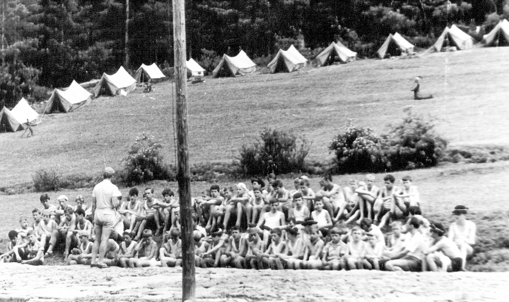 zdjęcie czarno-białe, zdjęcie przedstawia grupę dzieci w tle widać namioty rozstawione na polanie