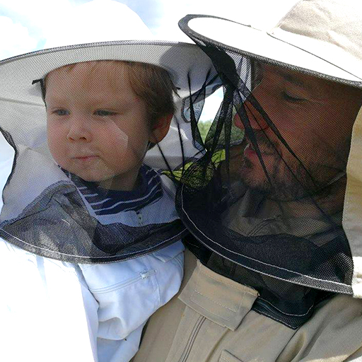 zdjęcie dyrektora cwr trzymającego syna na rękach w strojach pszczelarskich