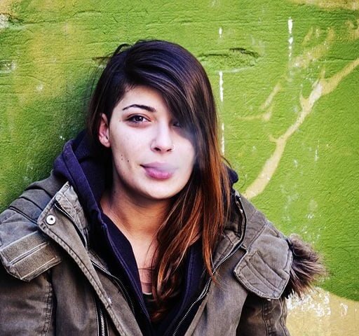 nastolatka w zimowej kurtce wypuszczająca dym z ust